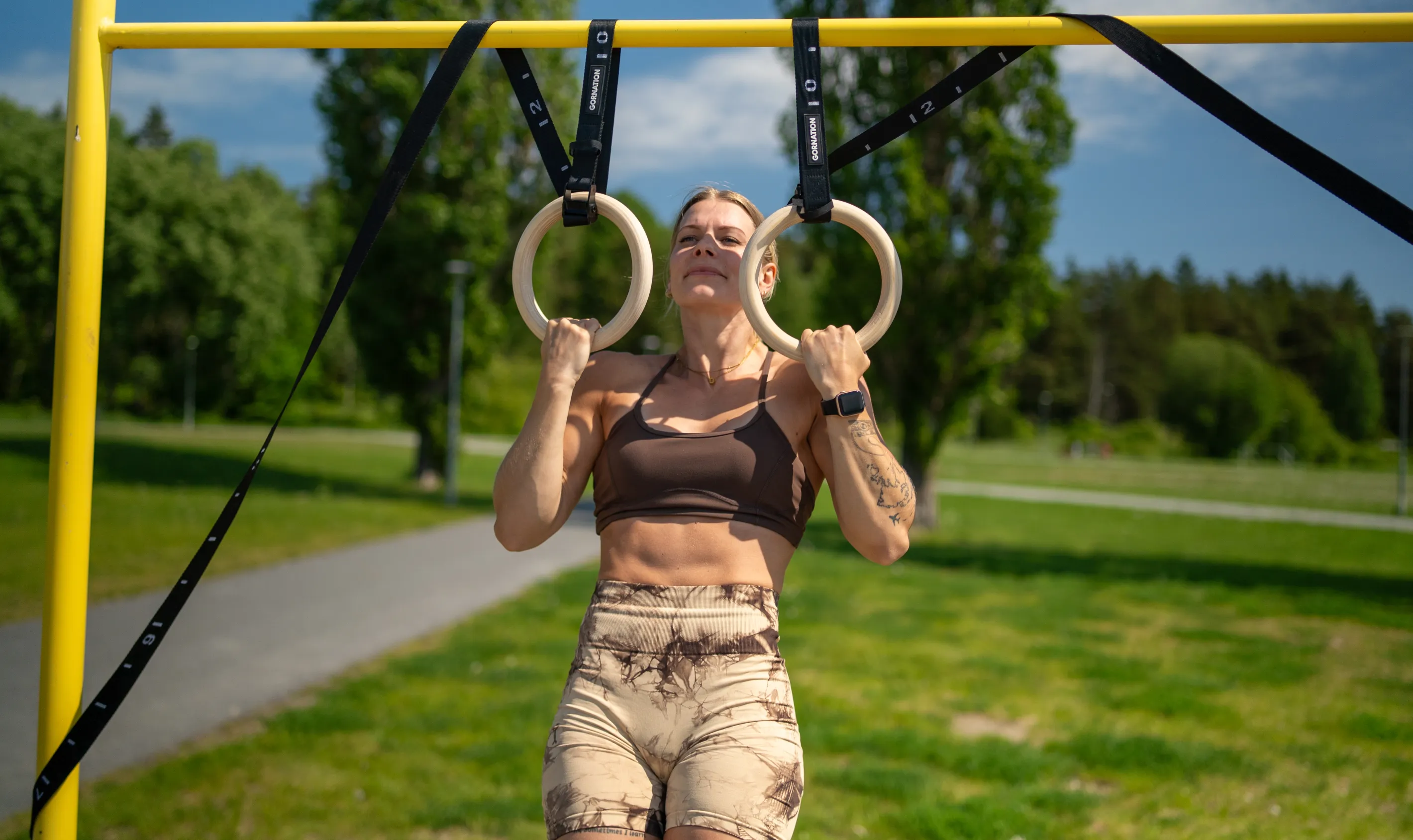 Coach tränar muscle-up i gymnastikringar utomhus